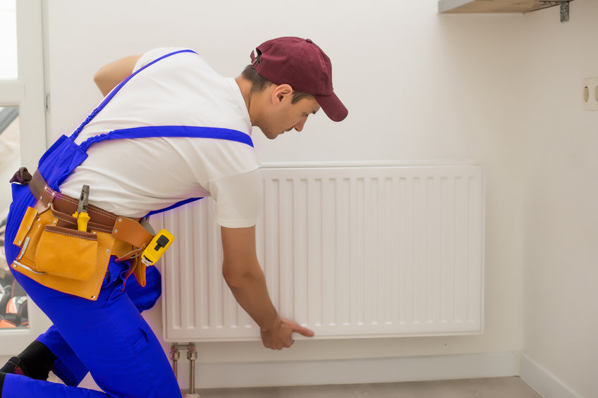 Technicien installant un radiateur mural blanc